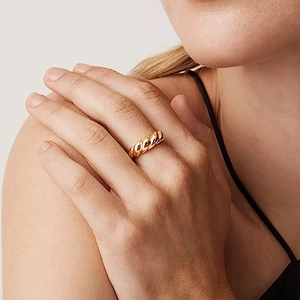Detailed close-up of a golden twisted rope croissant ring worn on a model index finger