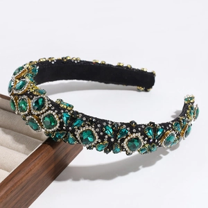 Macro shot of luxury green rhinestone headband with gold settings on a wooden tray