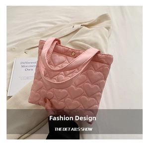 Detailed view of pink heart quilted fabric handbag with golden magnetic closure