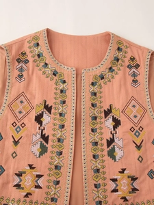 Close-up of pink-orange ethnic vest with colorful geometric embroidery and open front