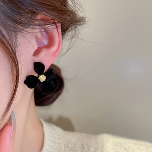 Close-up of elegant black velvet flower stud earrings worn by a model in a profile view