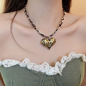 Close-up of leopard print heart pendant on a stylish leather choker necklace