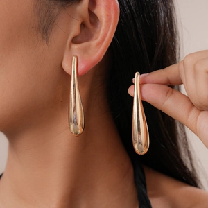 Detailed close-up of golden teardrop earrings being worn to show size and scale