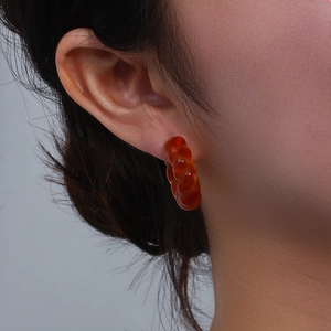 Gros plan détaillé d'une boucle d'oreille créole torsadée en résine ambre