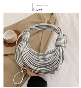 Detail of silver pleated knot handbag with metallic PU finish on a beige blazer