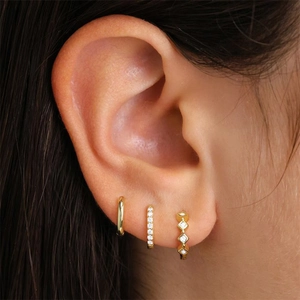 Detailed close-up of a three-piece gold earring set with marquise-cut cubic zirconia