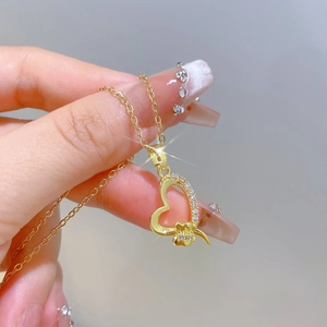 Macro detail of a golden heart necklace with small sparkling diamonds and flower charm