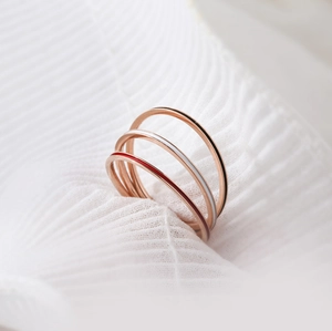 Detail of rose gold stackable rings with red white and black enamel on white fabric