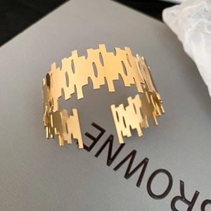 Macro view of gold-plated cuff bracelet featuring irregular geometric cutout patterns