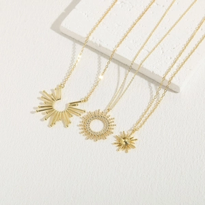 Three 14K gold plated sunflower pendant necklaces arranged on minimalist stone blocks