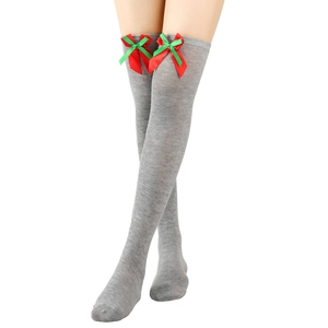 Detail of grey over-knee knitted socks featuring red and green ribbon bow decorations