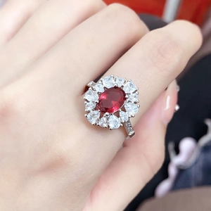 Elegante anello con tormalina rossa ovale e doppio alone floreale indossato al dito