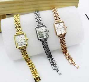 Detailed view of square quartz watches in gold, silver, and rose gold on a display stand