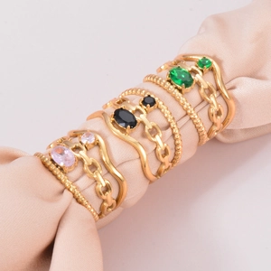 Three sets of gold stainless steel rings with zircon chain and gemstone inlays on silk