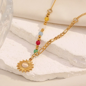 Detail of 18K gold-plated sun pendant necklace with colorful beads on textured stone