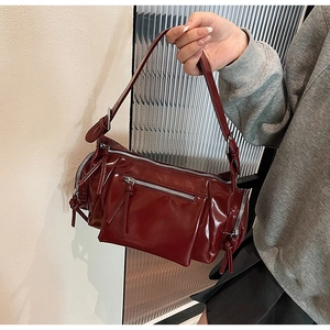 Détail du sac à bandoulière en similicuir bordeaux avec plusieurs poches zippées fonctionnelles