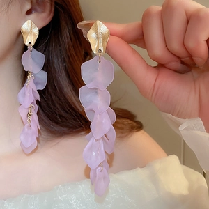 Detail of purple acrylic petal tassel earrings with golden leaf studs on model