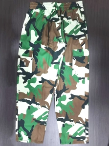 Detail view of camouflage cargo pants with drawstring waist on wood floor background