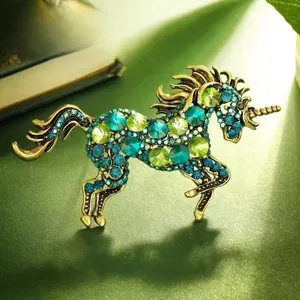 Macro view of vintage unicorn horse brooch with green gradient crystals and antique gold finish