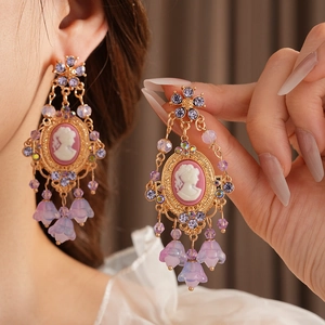 Close-up of vintage cameo earrings with purple crystals and flower tassel drops