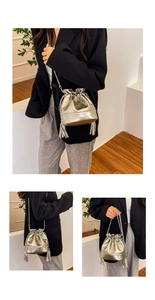 Detail showing silver bucket bag with pleated metallic texture, fringe and chain strap