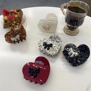 Flat lay of multiple acetic acid heart hair claws with bows in various stylish colors
