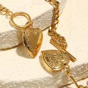 Detailed close-up of a gold heart locket pendant with floral rose embossing on the surface