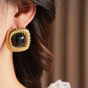 Details von Vintage Goldohrringen mit schwarzem ovalem Edelstein an einem Model
