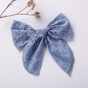 Detail of light blue embroidered cotton bow hair clip with intricate lace floral patterns