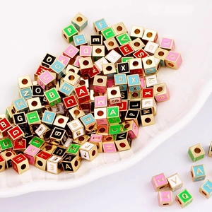 Macro view of colorful enamel alphabet beads with gold-plated frames for DIY jewelry