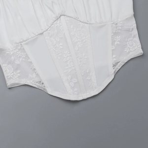 Detailed view of white lace patchwork corset top with floral rose patterns and curved hem