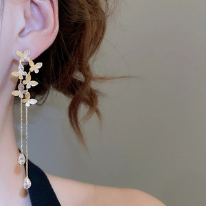 Close-up of gold butterfly tassel earrings with teardrop gems on a female model