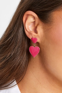 Close-up of pink enamel double heart dangle earrings in 18k gold plated finish