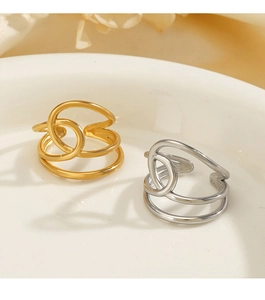 Détail de bagues croisées en acier inoxydable doré 18K et argent sur plateau blanc