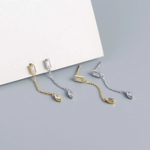 Close-up of gold and silver tassel earrings with bezel-set marquise cubic zirconia