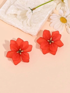 Detailed macro view of red acrylic flower earrings with golden metallic stamen centers