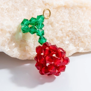 Macro detail of handmade red and green crystal cherry pendant with golden loop