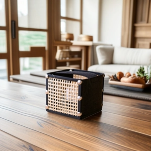 Foldable woven bamboo and fabric tissue box with metal rivets on a wooden table