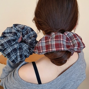 Detail of plaid fabric scrunchies showing woven texture and high elasticity on a bun