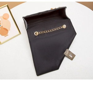 Top view of open black quilted crossbody bag with gold chain strap and square buckle lock