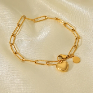 Detailaufnahme des 18K Gold Herzanhänger-Armbands auf elegantem champagnerfarbenem Seidenstoff