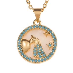 Detailed macro shot of a gold Aquarius zodiac pendant with white shell inlay and blue beads