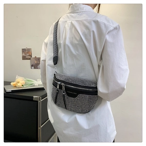 Detail of black crossbody chest bag with silver rivets and striped woven shoulder strap