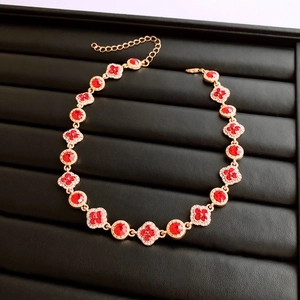 Détail du collier vintage doré avec pierres rouges facettées et motifs trèfle