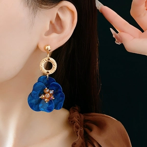 Detail of model wearing a vintage deep blue floral earring with amber bead center and gold ring