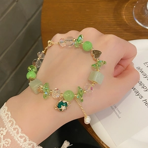 Close-up of a sweet green and clear beaded planet bracelet worn on a woman wrist