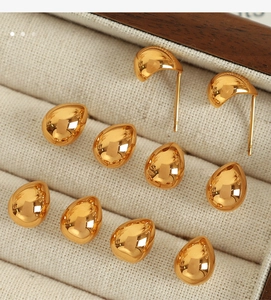 Detailed macro shot of golden teardrop stud earrings arranged in a fabric jewelry box