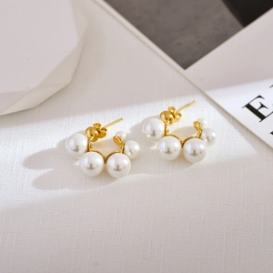 Elegant gold C-shaped hoop earrings with gradient pearls on a minimalist background