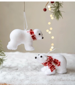 Detailed view of white flocked polar bear ornaments with red checkered scarves on snow