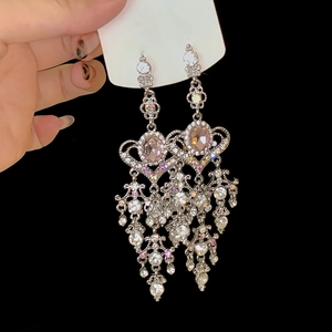 Detail of silver drop tassel earrings featuring a large pink gemstone and rhinestones